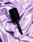 Smoothing Paddle Brush -- InStyler-lifestyle photo of brush on purple silk fabric