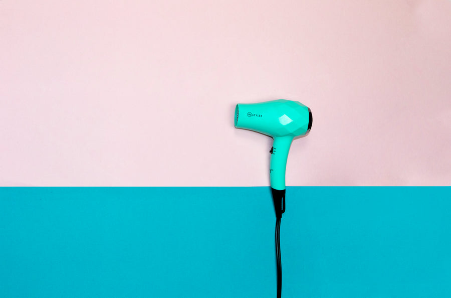 Limited Edition MINI hair dryer on color-blocked pink and turquoise background