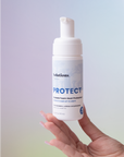 Model holding PROTECT Foam Heat Protectant bottle-InStyler