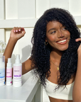 Photo of model with curly black hair sitting next to HOLD Volumizing Hair Spray-InStyler